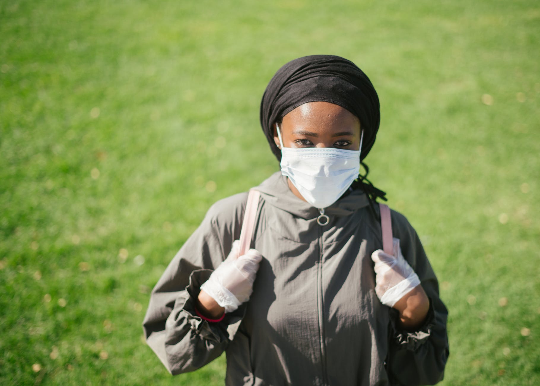 ethnic woman in protective mask and gloves on lawn