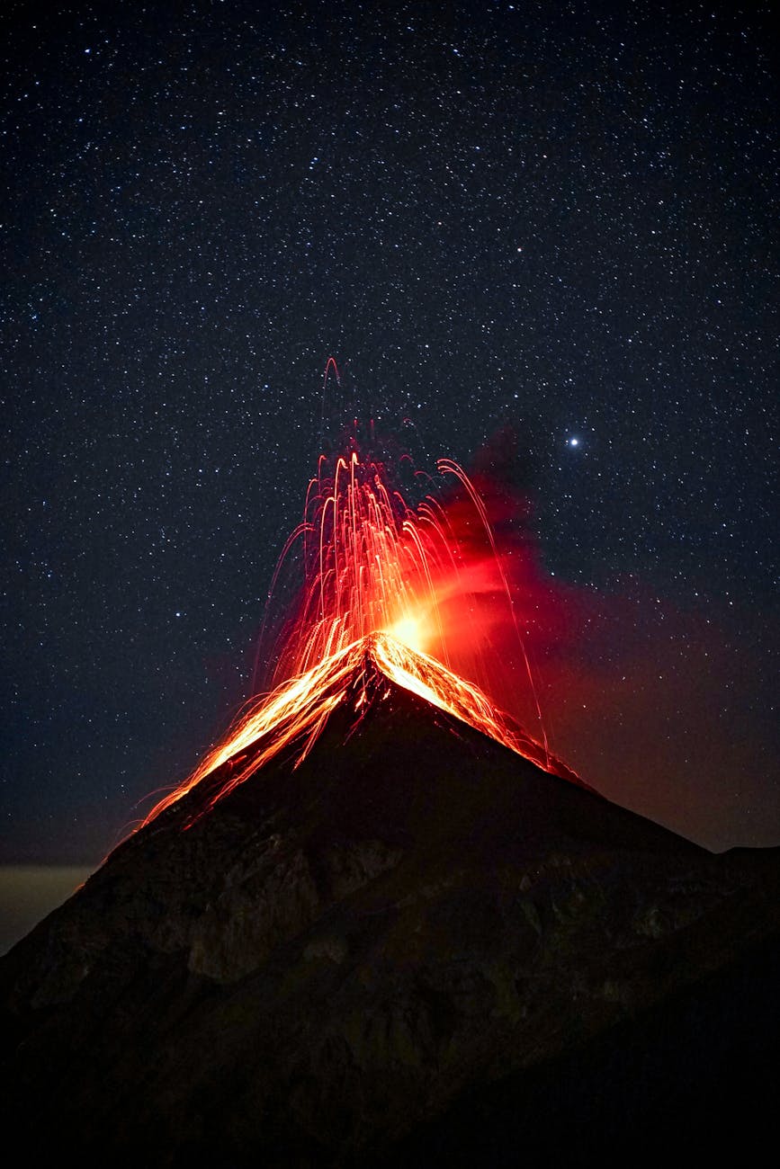 volcano erupting at night under starry sky